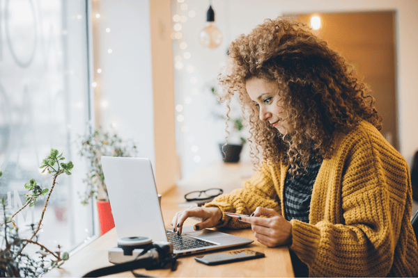 Image of a woman potentially donating to a nonprofit online as she holds a credit card and looks at her laptop