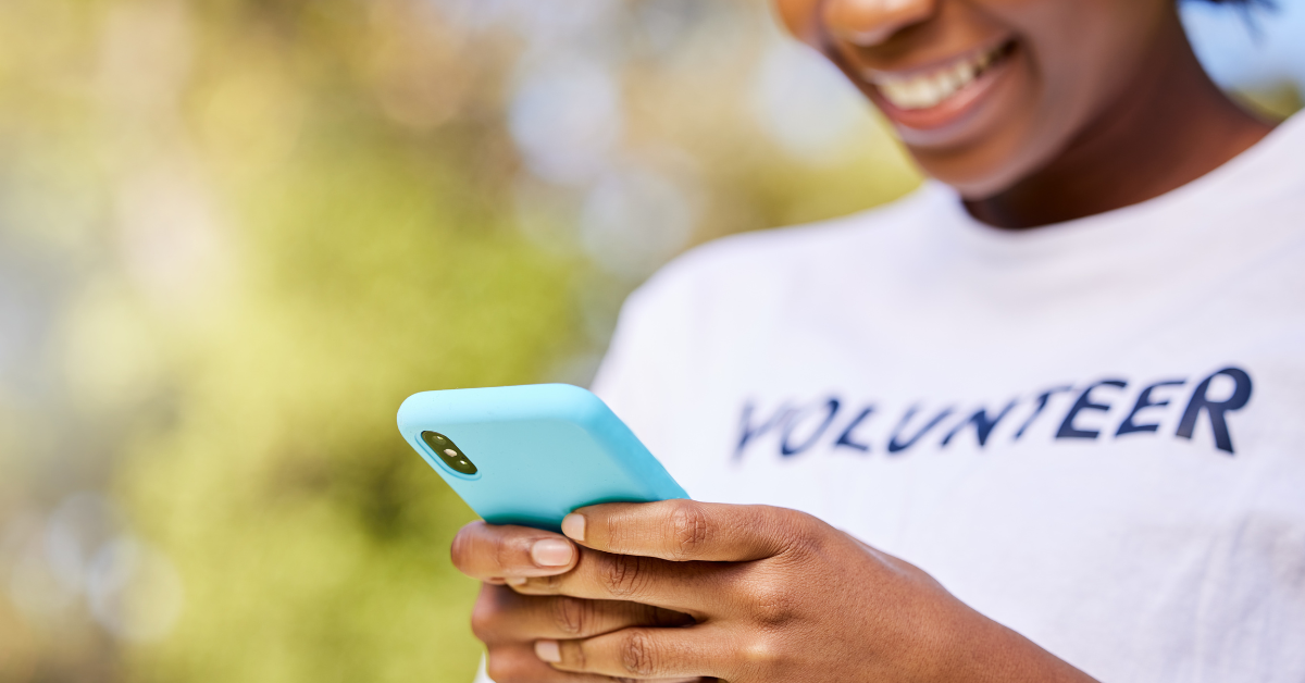 Image of a young woman wearing a shirt that says volunteer looking at cell phone