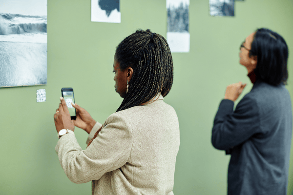 Image of a woman scanning a QR code of a piece of art with a second person in the background