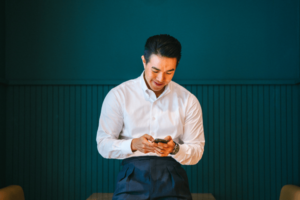 Image of a man in a white shirt looking at a phone