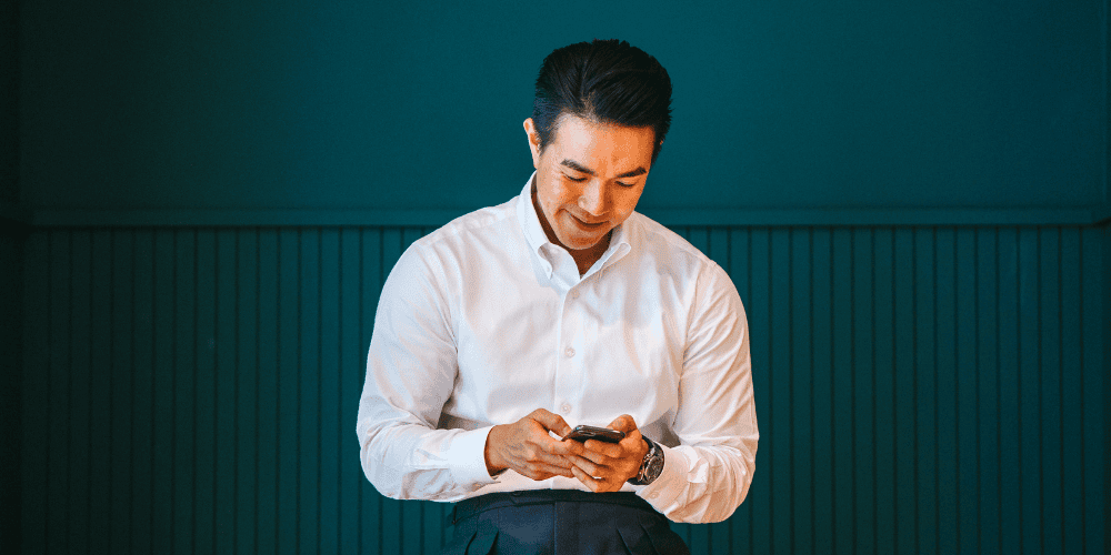 Image of a man in a white shirt looking at a phone