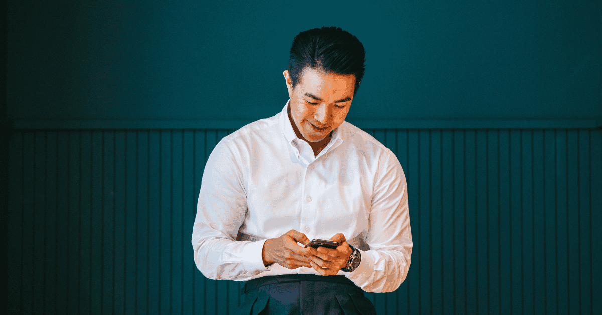 Image of man in a white shirt looking at a phone